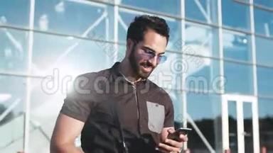 一个戴着太阳镜的年轻大胡子壮汉离开机场，用他的手机，高兴地对它微笑。 社会网络